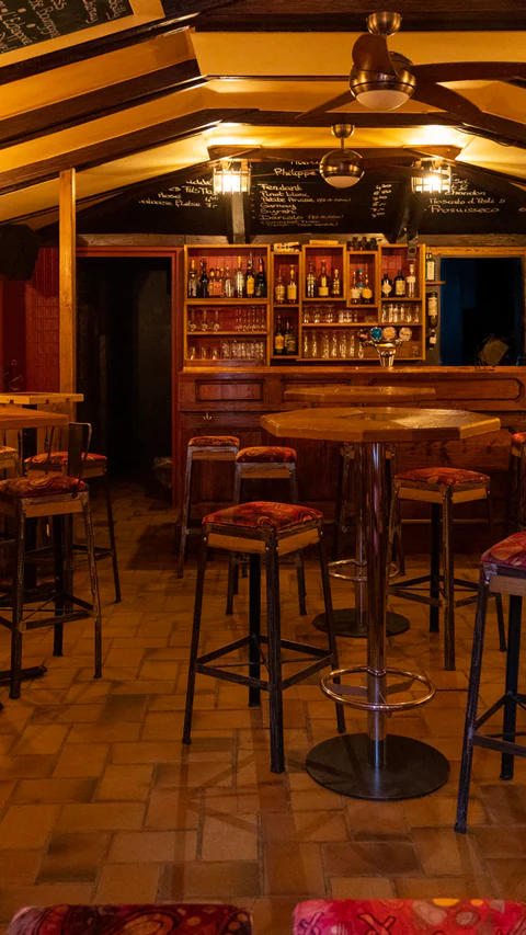 Interior view of La Gouttière with its bar counter, red seating and wrought-iron furniture.